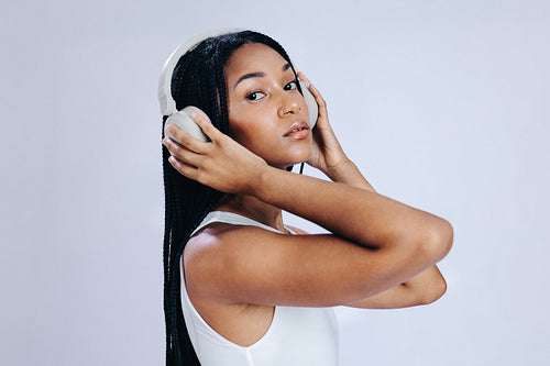 Young woman looking at the camera while listening to music on headphones