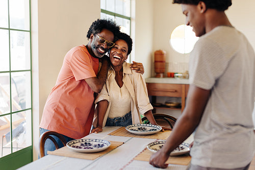 Parents and their son setting the table for a happy family breakfast