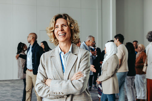 Happy female CEO at a business conference with diverse colleagues in the background