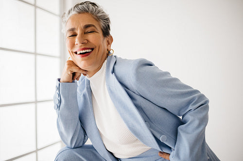 Successful business woman with silver hair smiling at the camera, wearing a classy business suit