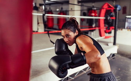 Female fighter ducking after striking a punching bag