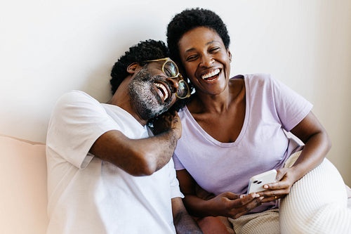 Mature couple laughing and browsing a smartphone together