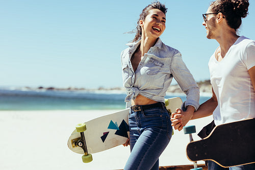 Smiling couple together at the beach with skateboards