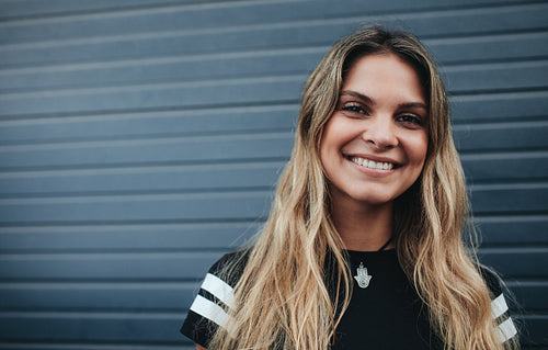 Smiling young female standing against gray wall