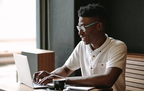 Freelancer working on laptop computer at coffee shop