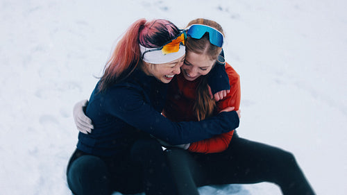 Women share a playful hug before running on a winter training day