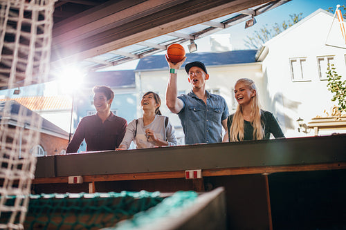 Young people playing basketball game at amusement park