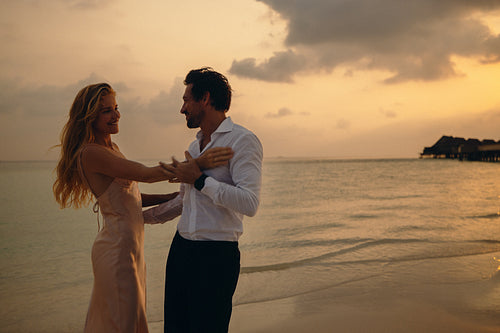 Romantic couple dancing at sunset on a dreamy honeymoon beach
