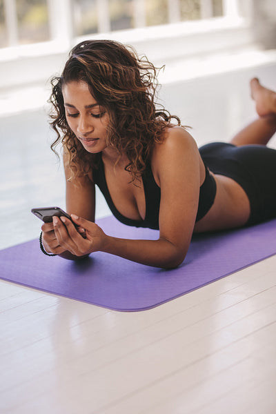 Woman relaxing at yoga class with a cellphone