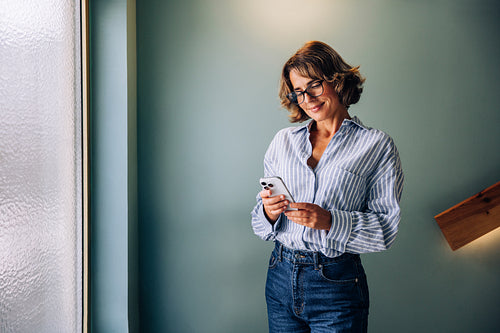 Professional woman using a smartphone while standing indoors