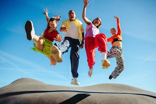 Friends jumping in the air outdoors against a clear blue sky