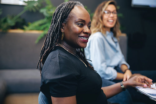 Mature African business woman sitting in a meeting, engaging in a discussion with her team