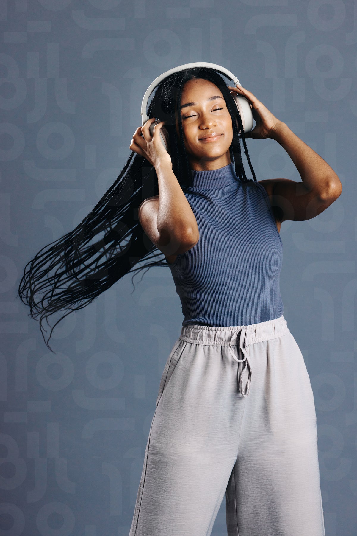 Young woman with braids enjoying listening to music on headphones ...