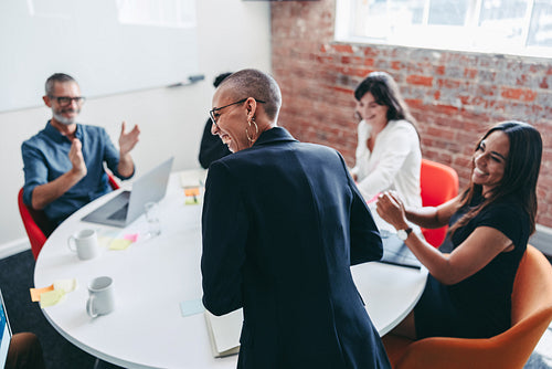 Woman being applauded by her team in an office