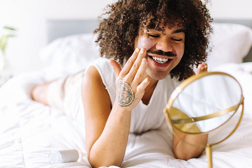 Nonconforming young man applying makeup to his face