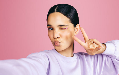 Self expression with a selfie: Fun young woman taking a picture of herself in a studio