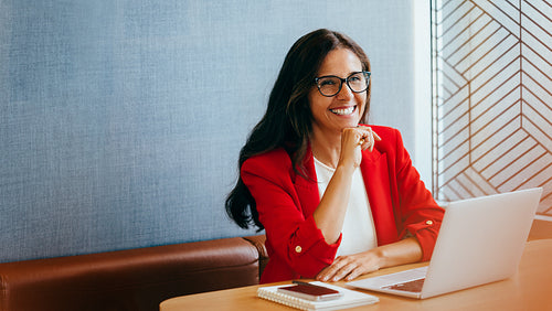 Confident professional woman working on a laptop and smiling during a meeting