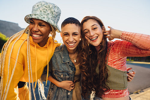 Female friends smiling while embracing each other outdoors