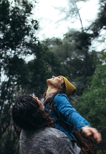 Couple enjoying themselves in rain at forest