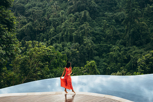 Beautiful woman walking on edge of infinity pool