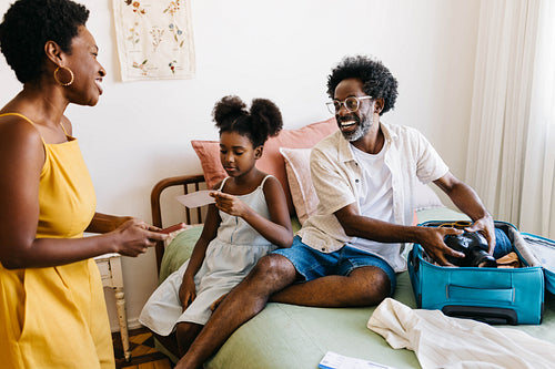 Happy black family packing travel essentials for a cheerful vacation together