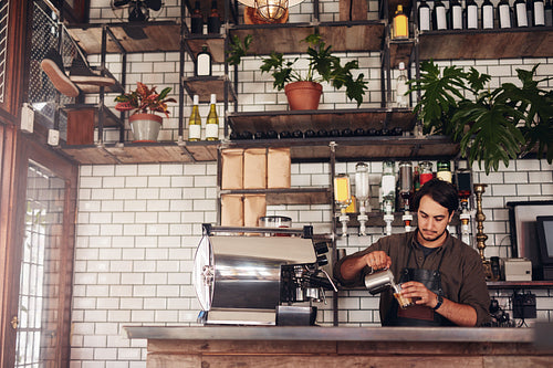 Young male barista making a cup of coffee