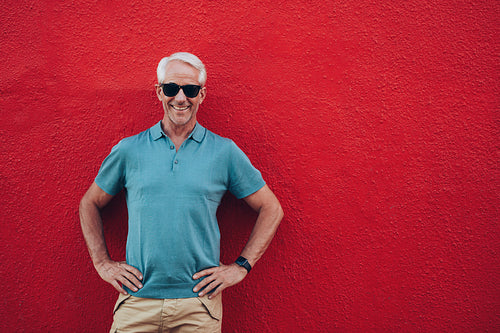 Confident mature man standing on red background