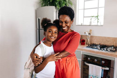 Happy stay at home mom hugging her daughter goodbye before she leaves for school in the morning