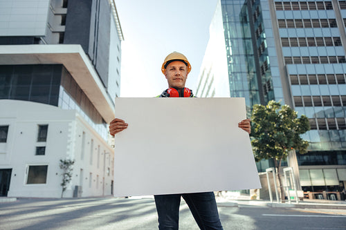 Blue collar worker holding a blank placard in the city