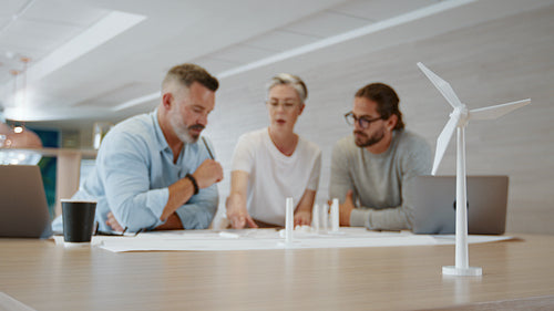 Wind turbine design: Sustainable engineering team having a discussion using 3D drawings and models in an office