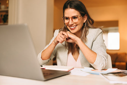 Smiling designer attending a virtual meeting in her home office