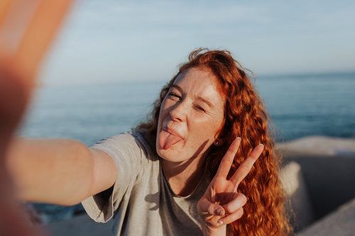 Young woman taking a selfie next to the sea