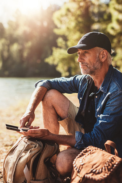 Senior hiker sitting by a lake on summer day