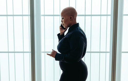 Focused black woman using phone in bright modern office setting