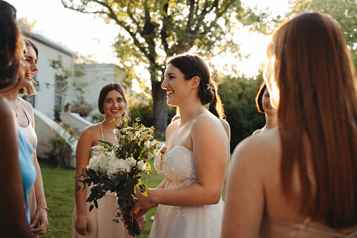 Smiling bride sharing a joyful moment with bridesmaids during outdoor wedding celebration