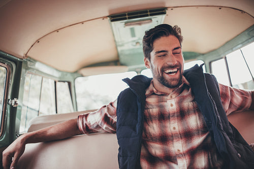 Laughing man traveling in a van on roadtrip