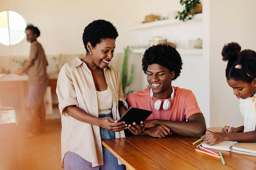 Happy mother and son learning together at home using tablet device