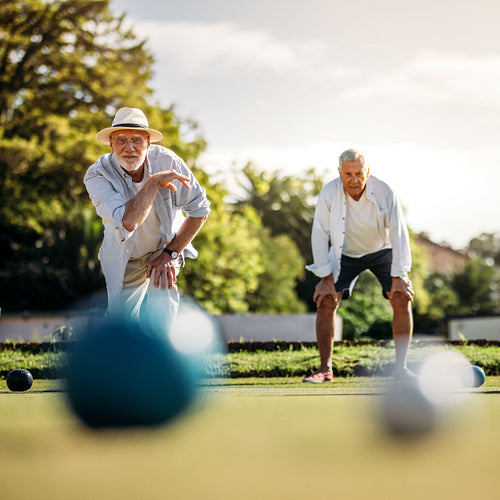 Senior man throwing a boules standing in position