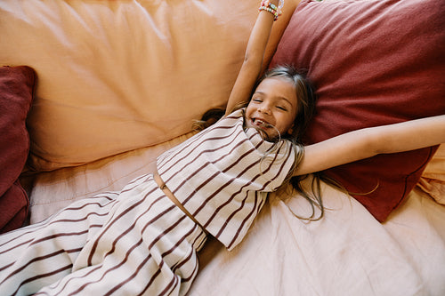 Bright child smiling and stretching on a bed