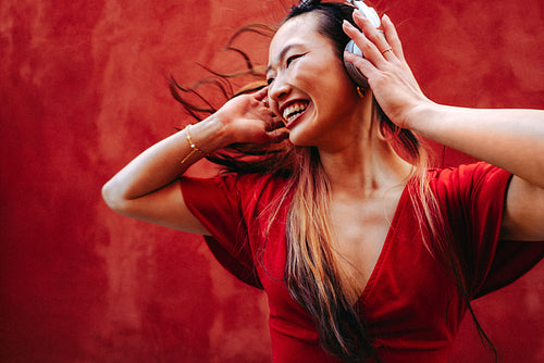 Smiling woman dances with headphones while enjoying music outdoors