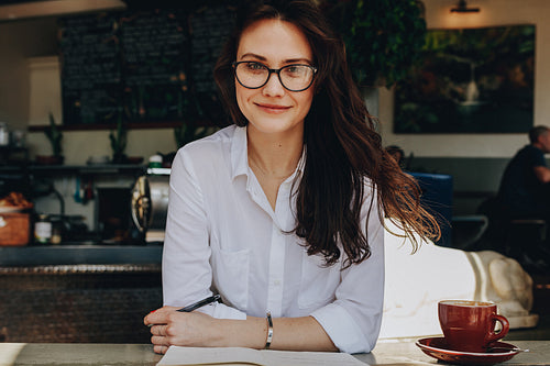 Woman at cafe with notebook and coffee on table