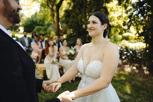 Bride and groom holding hands at outdoor wedding in a scenic garden setting