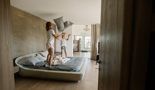 Mother and son playing with pillows in bedroom
