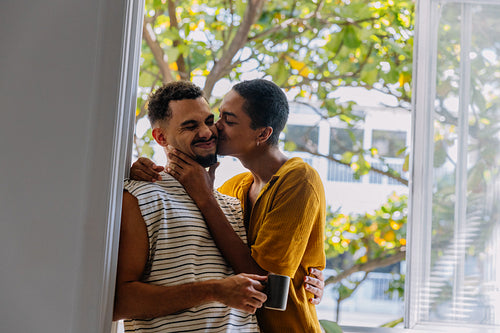 Loving couple sharing a tender moment by the window with coffee