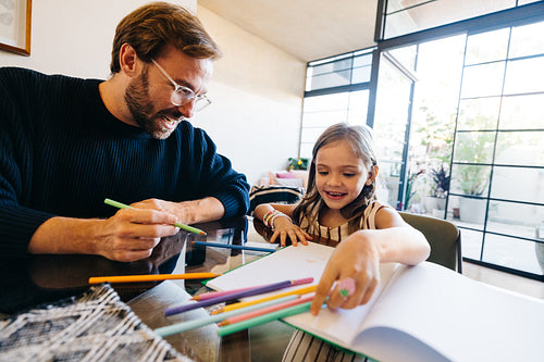 Father and daughter coloring together at home