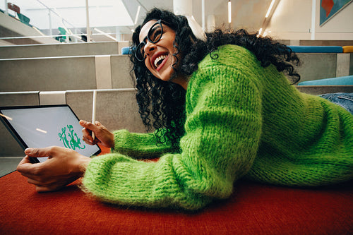 The smiling woman enjoys digital creativity on library steps with a tablet