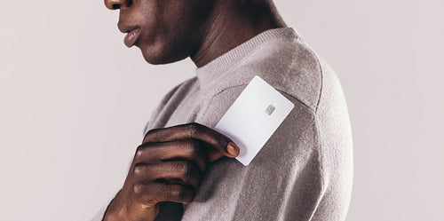 Professional black man holding his credit card in his hand while standing in a studio