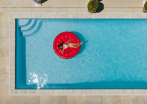 Woman relaxing on floating mattress in pool