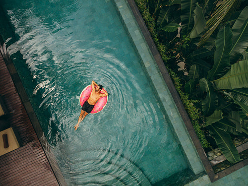 Young man relaxing on inflatable ring in resort pool