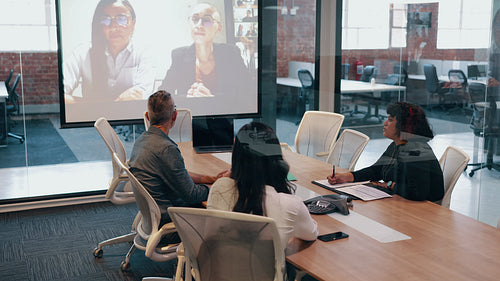 Video conference in a boardroom: Business people connecting with remote colleagues in an office